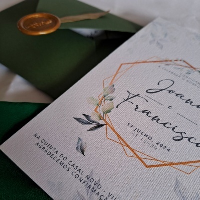Convite de casamento branco com detalhes laranja e verdes, envelope verde com selo de cera dourado