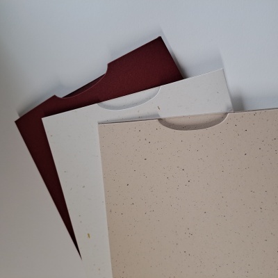 Pastas de papel texturizado nas cores bordô, branco e bege com manchas pontilhadas