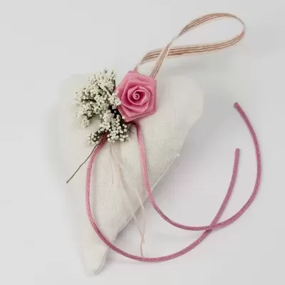 Coração tecido branco decorado com flor rosa e fitas em fundo branco