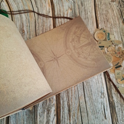 Livro aberto com desenho de bússola em páginas castanhas sobre madeira cinzenta