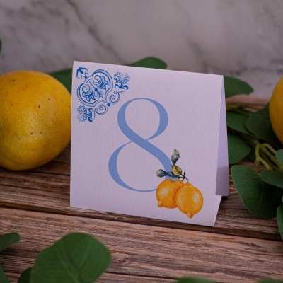 Cartão branco com número 8 azul e ilustração de limões em mesa de madeira com limões e folhas