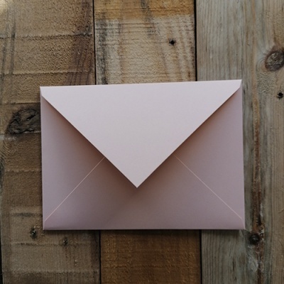 Envelope cor-de-rosa sobre madeira rústica