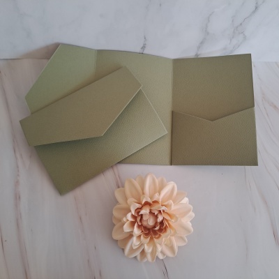 Carteira de papel reciclado verde-oliva com textura granulada junto a flor rosa claro