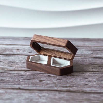 Caixa de anéis em madeira com interior cinzento sobre superfície de madeira