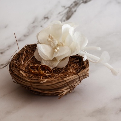 Cesto de ramos secos com alianças douradas e flor branca artificial