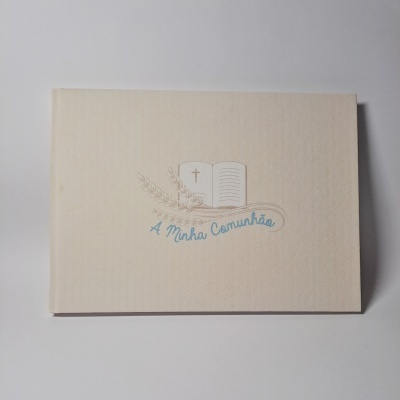 Livro ou álbum bege com inscrição 'A Minha Comunhão'