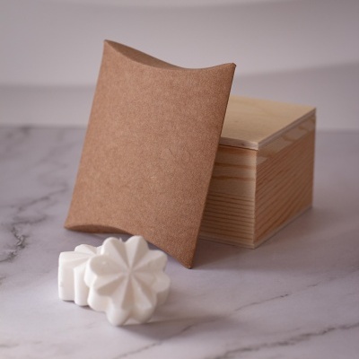 Sabonetes brancos em formato de flor com embalagem castanha e caixa de madeira sobre mármore