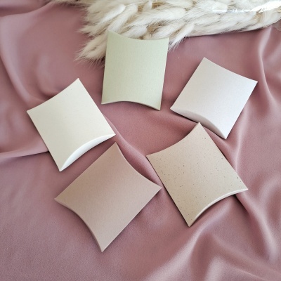 Cinco caixas pequenas almofada em tons neutros sobre tecido rosa