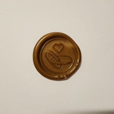 Selo de cera dourada com relevo de coração numa superfície branca