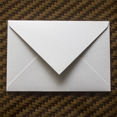 Envelope branco fechado sobre superfície castanha texturizada