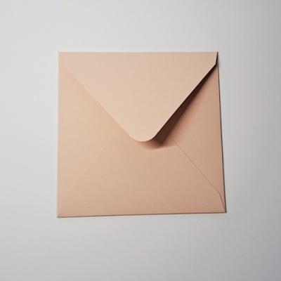 Envelope quadrado cor de salmão claro sobre superfície branca