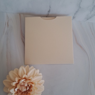 Caixa bege com textura e flor decorativa branca sobre superfície marmoreada clara