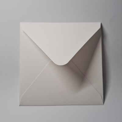 Envelope quadrado branco com aba virada para cima sobre superfície branca