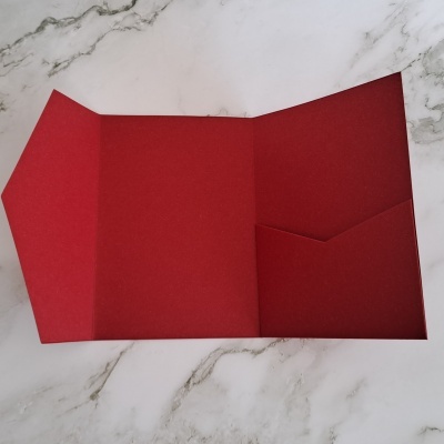 Envelope vermelho aberto com bolso interior sobre superfície de mármore branco