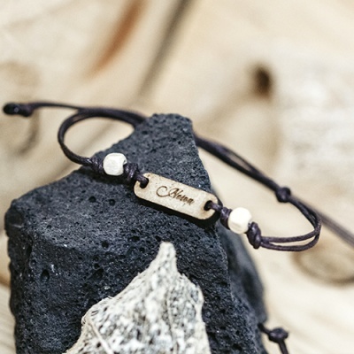 Pulseira com cordão castanho, contas brancas e placa metálica gravada com a palavra Amor