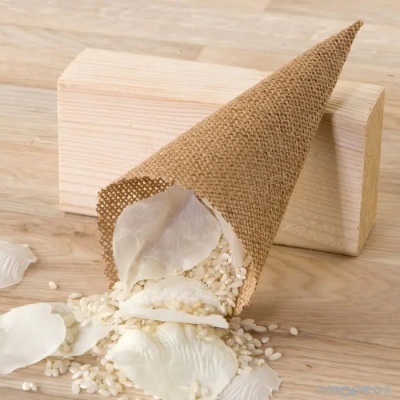 Cone de rede castanha com pétalas e grãos brancos sobre madeira clara