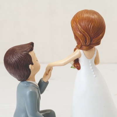 Figuras decorativas de noivo ajoelhado e noiva de vestido branco