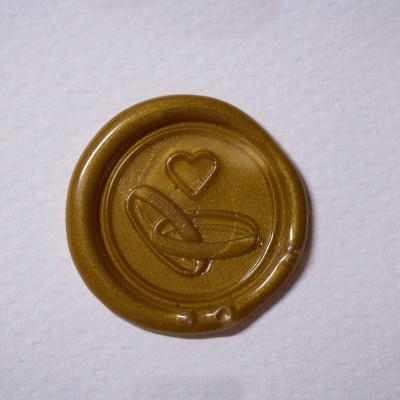 Selo de cera dourada com coração e anéis entrelaçados