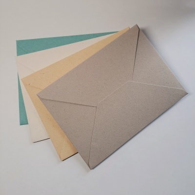 Envelopes coloridos em papel reciclado com textura, dispostos em leque