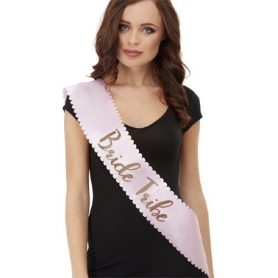 Mulher com vestido preto e faixa rosa claro escrita Bride Tribe