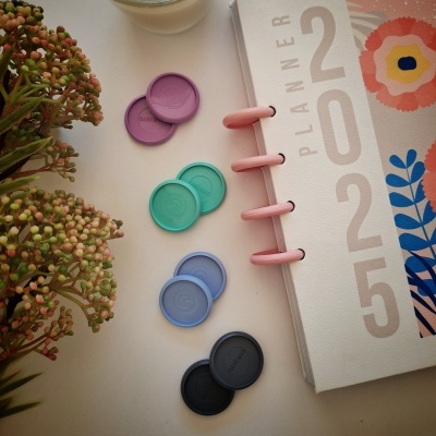 Planner branco com argolas rosa e tampas coloridas ao lado