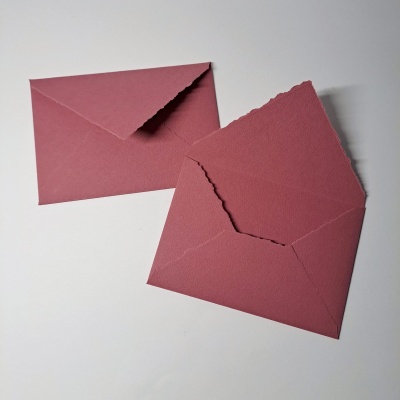 Dois envelopes rosa escuro em papel texturizado sobre fundo branco