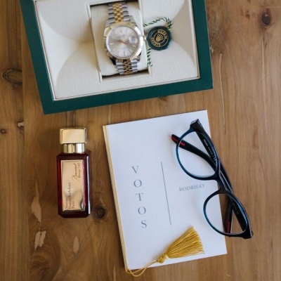Relógio, perfume, caderno com votos e óculos sobre mesa de madeira
