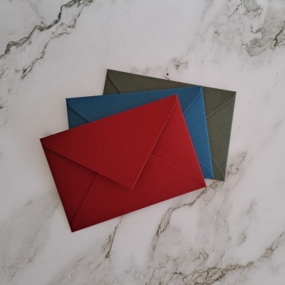 Três envelopes coloridos sobre superfícies de mármore branco