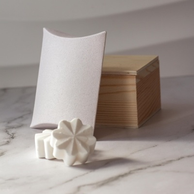 Conjunto de sabonetes brancos em forma de flor com caixa de madeira clara