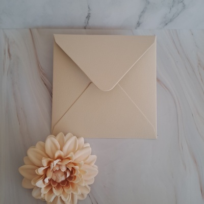 Envelope bege sobre superfície mármore com flor decorativa bege