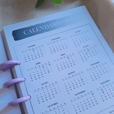 Calendário 2024 impresso com meses em tabela em papel branco num livro com argolas roxas