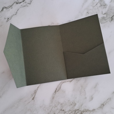 Pasta em papel cartão verde escuro com bolso interno sobre mármore branco