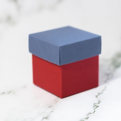 Caixa pequena de presente azul e vermelha numa superfície branca