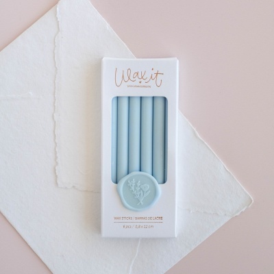 embalagem branca com cinco velas azuis claras e selo azul com ramo florido, marca Wax it