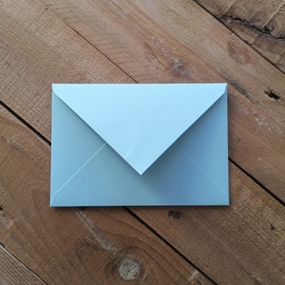 Envelope azul claro sobre mesa de madeira