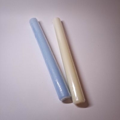 Dois bastões cilíndricos azul claro e creme embalados em plástico
