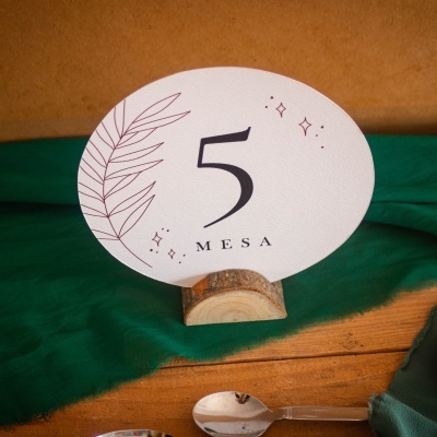 Placa de mesa número 5 com base de madeira sobre tecido verde