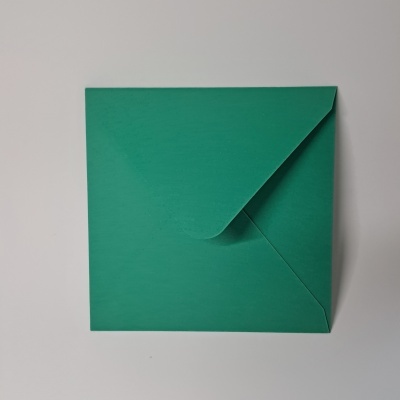 Envelope verde quadrado sobre superfície branca