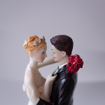 Figuras decorativas de noivos em porcelana com ramo de flores vermelhas