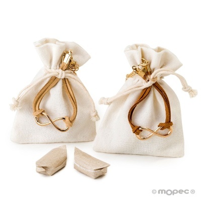 Duas pulseiras douradas com elos em forma de infinito em sacos de pano branco com peças retangulares bege