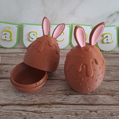 Duas caixas em forma de ovos de chocolate com orelhas de coelho, uma aberta e outra fechada.