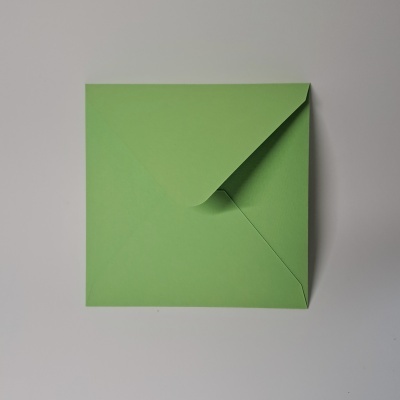 Envelope verde quadrado sobre superfície branca