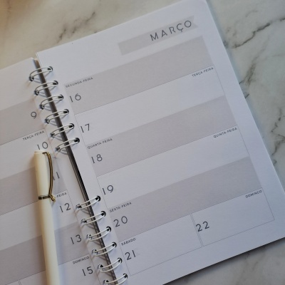 Calendário semanal aberto com caneta sobre superfície de mármore