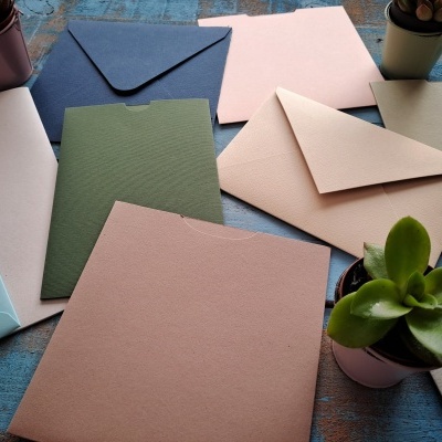 Conjunto de envelopes coloridos e plantas suculentas em mesa azul