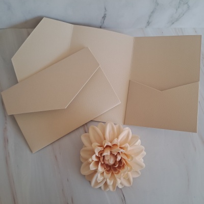 Envelope e cartão creme texturizados com flor decorativa ao lado