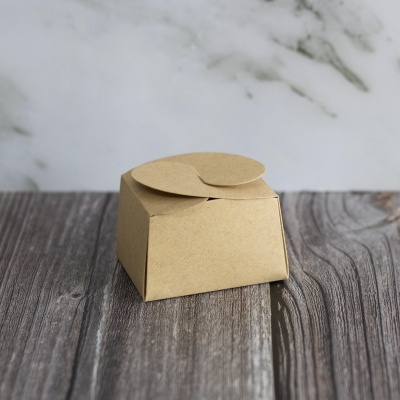 Caixa pequena de cartão castanho claro em superfície de madeira escura