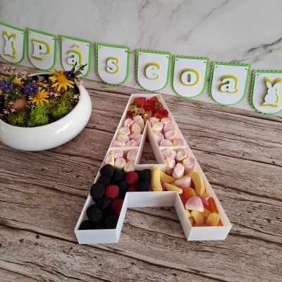 Organizador letra A branco com gomas coloridas e decoração PÁSCOA ao fundo