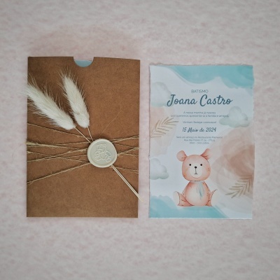 Convite de batismo com desenho de urso e envelope castanho com selo de cera e penas brancas