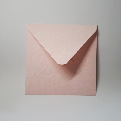 Envelope quadrado de papel rosa claro fechado sobre superfície branca