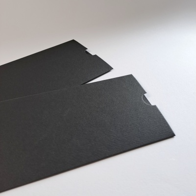 Envelopes ou capas finas pretas de papel cartão com recorte semicircular sobre superfície branca